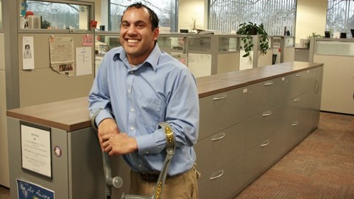 picture of man in blue shirt leaning against a filing cabinet